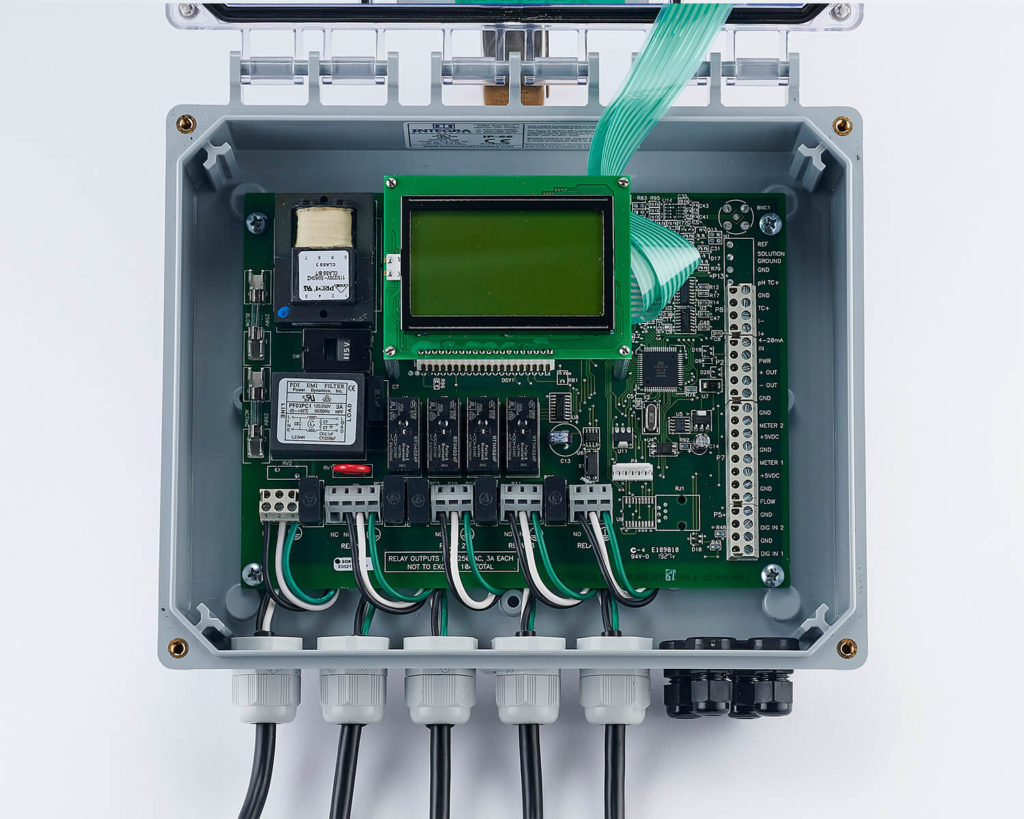 Electronic control system with LCD display, multiple connectors, and ribbon cable in a mounted gray box.